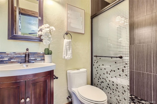 bathroom featuring vanity, toilet, and backsplash