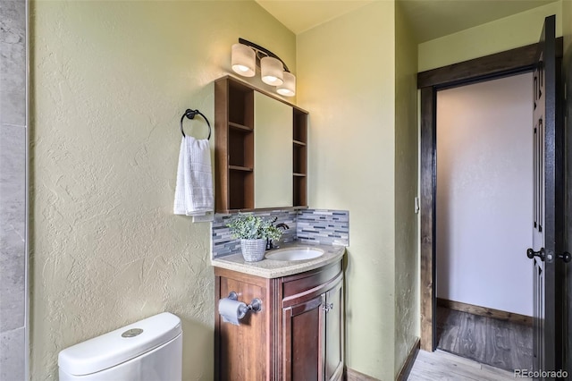 bathroom featuring hardwood / wood-style floors, vanity, toilet, and backsplash