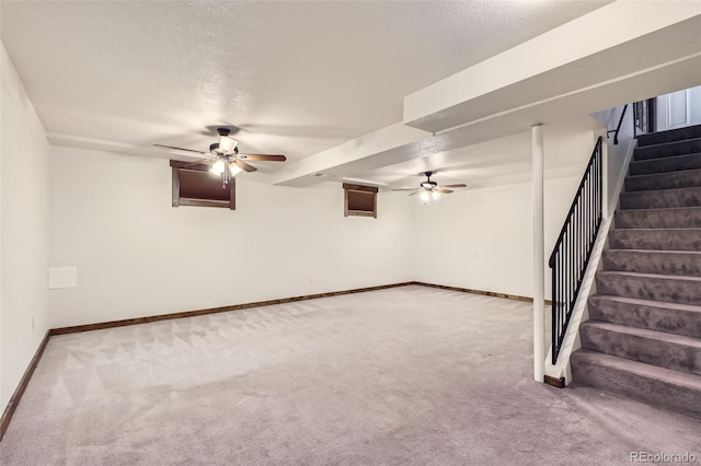 basement with ceiling fan, carpet, and a textured ceiling