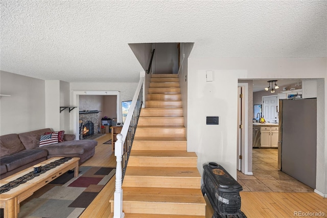 1024 S Mobile St, Aurora, CO 80017 - stairway with a textured ceiling, a brick fireplace, and tile patterned flooring