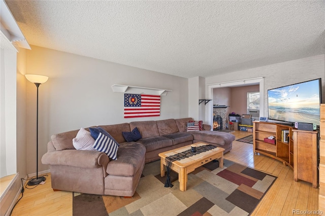 1024 S Mobile St, Aurora, CO 80017 - living room featuring light wood-style flooring, a textured ceiling, and a brick fireplace