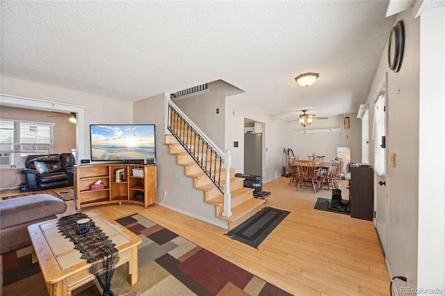 1024 S Mobile St, Aurora, CO 80017 - living area featuring a ceiling fan, light wood-style flooring, stairs, and a textured ceiling