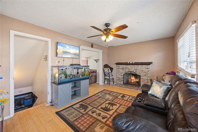 1024 S Mobile St, Aurora, CO 80017 - living room featuring a ceiling fan, light wood finished floors, a textured ceiling, and a brick fireplace