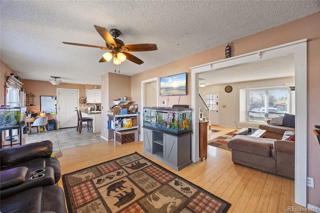 1024 S Mobile St, Aurora, CO 80017 - living room featuring ceiling fan, stairway, a textured ceiling, and light wood-style flooring