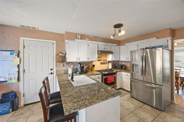 1024 S Mobile St, Aurora, CO 80017 - kitchen featuring appliances with stainless steel finishes, under cabinet range hood, white cabinets, a kitchen breakfast bar, and a peninsula