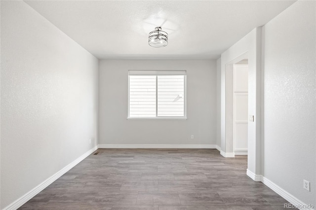 spare room with wood finished floors and baseboards