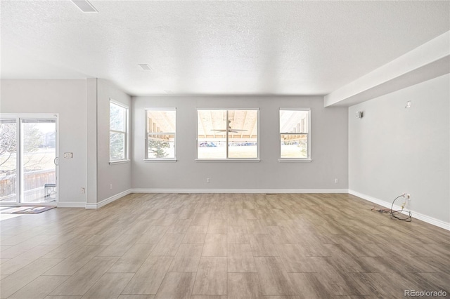 unfurnished living room featuring light wood finished floors, baseboards, and a textured ceiling