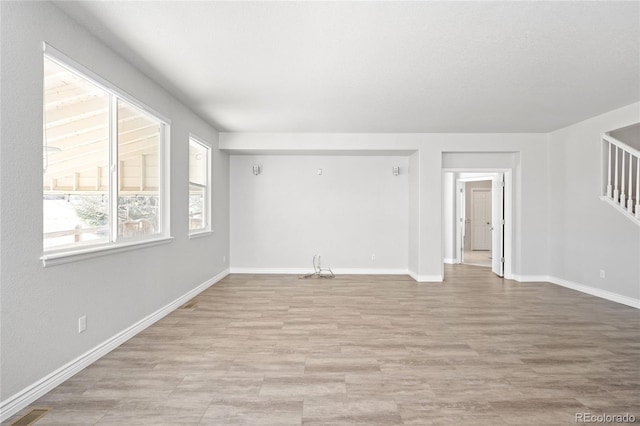 unfurnished living room with stairs, light wood-type flooring, visible vents, and baseboards