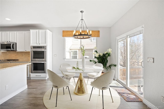 dining space with a wealth of natural light, baseboards, a notable chandelier, and light wood finished floors