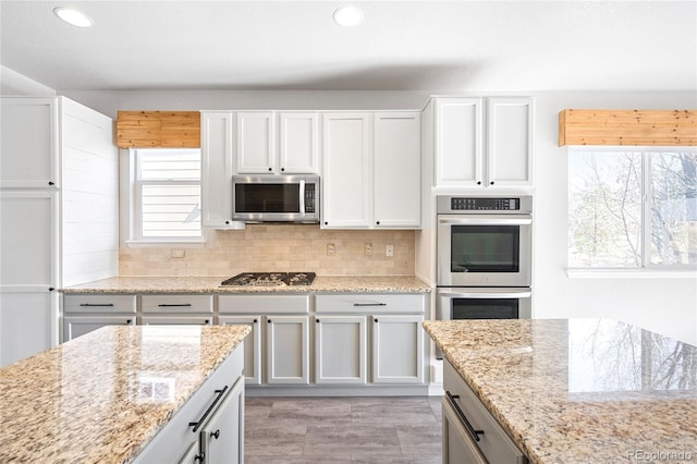 kitchen with light stone countertops, appliances with stainless steel finishes, decorative backsplash, and recessed lighting