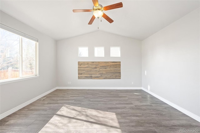 spare room featuring vaulted ceiling, wood finished floors, a ceiling fan, and baseboards