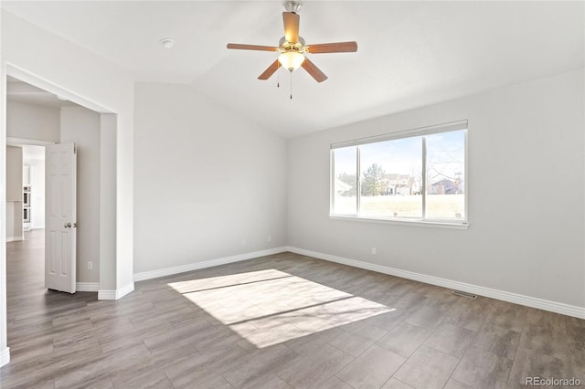 unfurnished room featuring visible vents, ceiling fan, vaulted ceiling, wood finished floors, and baseboards