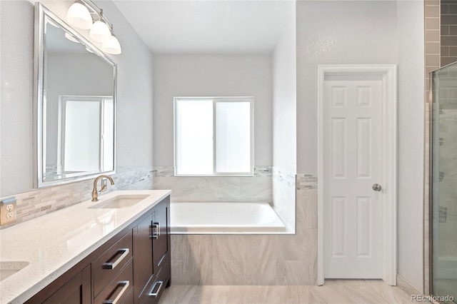 bathroom featuring double vanity, tiled tub, a sink, and tiled shower