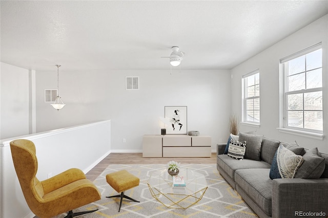 living area featuring visible vents, ceiling fan, baseboards, and wood finished floors