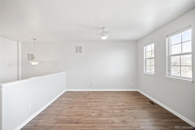 empty room featuring visible vents, baseboards, and wood finished floors