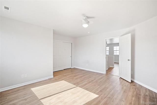 empty room with a ceiling fan, light wood-type flooring, visible vents, and baseboards