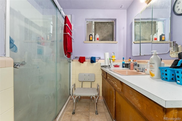 bathroom featuring vanity, tile patterned flooring, a shower with door, and tile walls