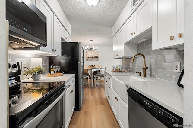 kitchen featuring stainless steel appliances, light countertops, light wood-style floors, a textured ceiling, and white cabinetry