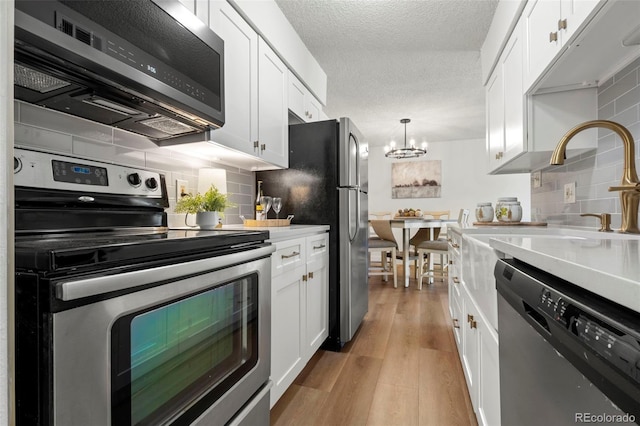 kitchen featuring light countertops, white cabinets, light wood-style floors, appliances with stainless steel finishes, and tasteful backsplash