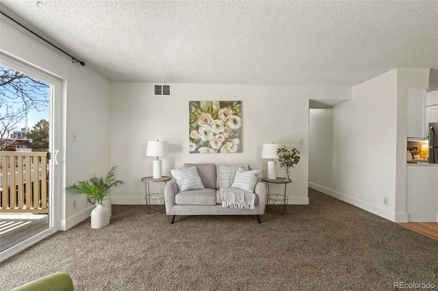 sitting room featuring visible vents, carpet floors, a textured ceiling, and baseboards