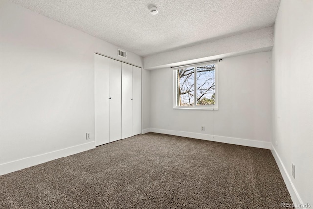 unfurnished bedroom featuring carpet, visible vents, baseboards, a closet, and a textured ceiling