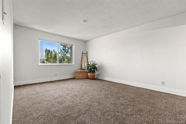 spare room featuring a textured ceiling, baseboards, and carpet