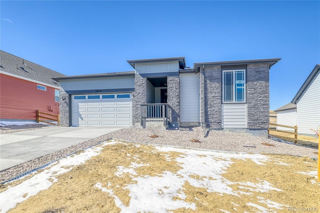 prairie-style home with an attached garage, stone siding, and driveway