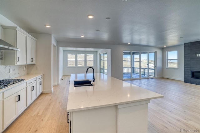 kitchen with a sink, tasteful backsplash, open floor plan, gas stovetop, and a fireplace