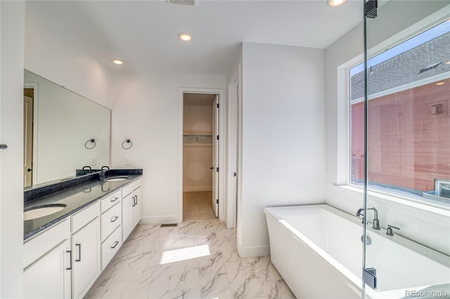 bathroom with a freestanding bath, plenty of natural light, marble finish floor, and a sink