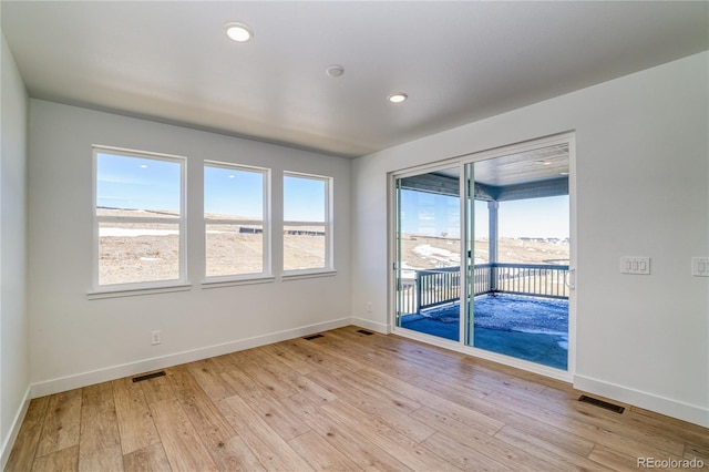 unfurnished room with light wood-type flooring, visible vents, baseboards, and recessed lighting