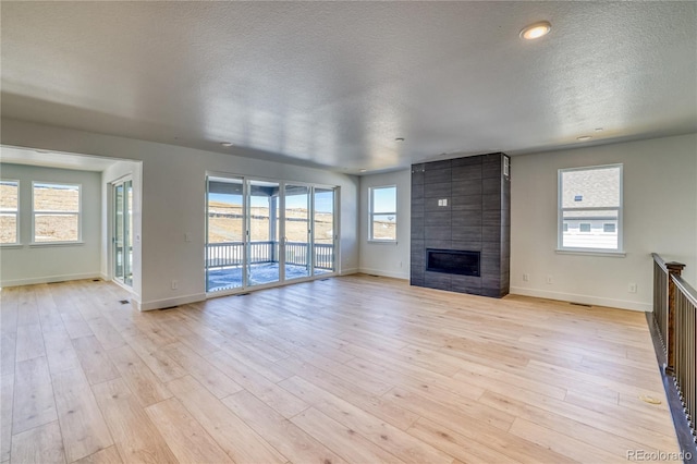 unfurnished living room with a fireplace, light wood-style floors, and a wealth of natural light