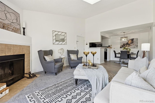 living room featuring a tiled fireplace, baseboards, and high vaulted ceiling