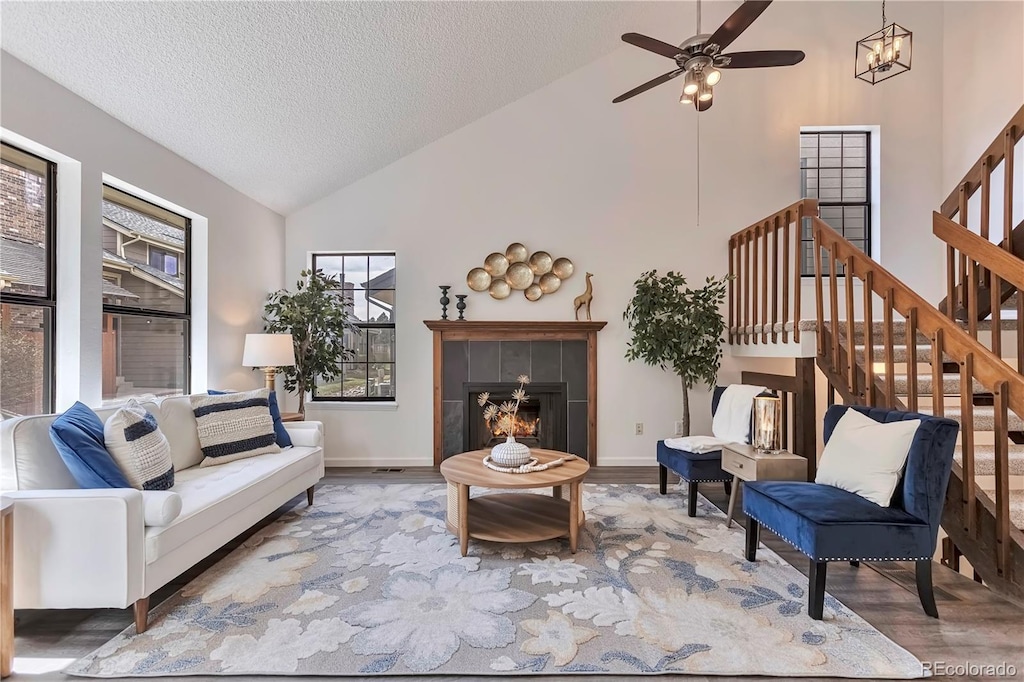 10836 W Evans Ave Unit 32, Lakewood, CO 80227 - living room with a ceiling fan, wood finished floors, stairway, a tile fireplace, and high vaulted ceiling