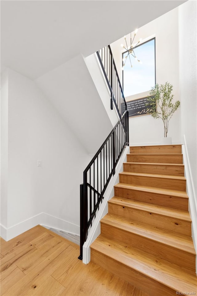 stairs with a chandelier and hardwood / wood-style floors