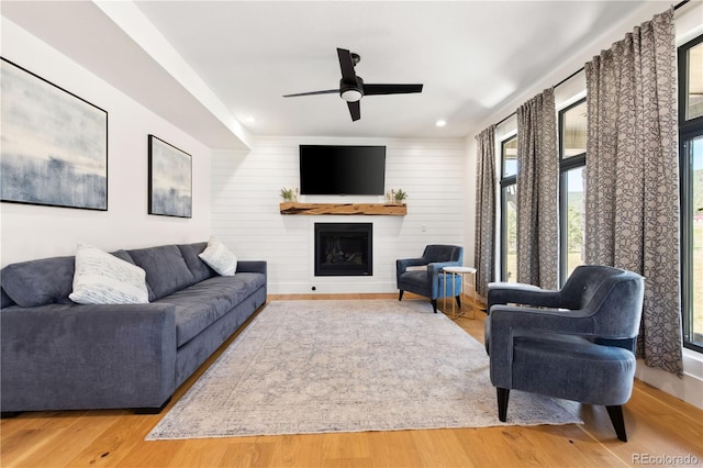 living room featuring ceiling fan, a fireplace, and light hardwood / wood-style flooring