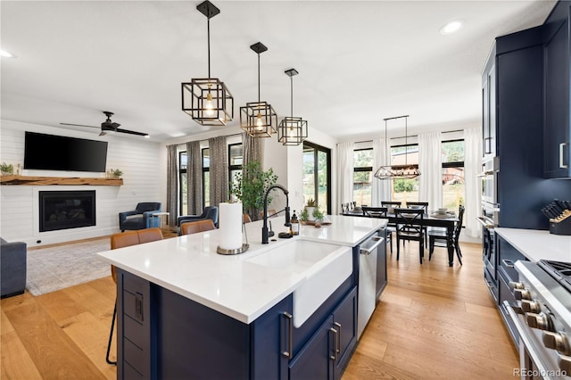 kitchen featuring pendant lighting, a breakfast bar area, blue cabinetry, a kitchen island with sink, and stainless steel appliances