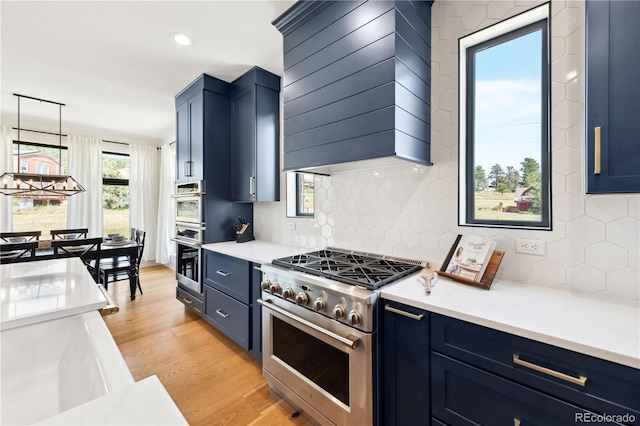 kitchen with blue cabinetry, premium range hood, stainless steel appliances, decorative backsplash, and light wood-type flooring