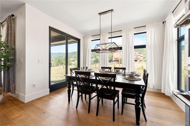 dining space featuring a mountain view, an inviting chandelier, and light hardwood / wood-style floors