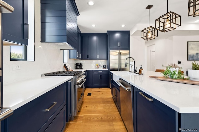 kitchen featuring decorative light fixtures, high quality appliances, blue cabinets, backsplash, and light wood-type flooring