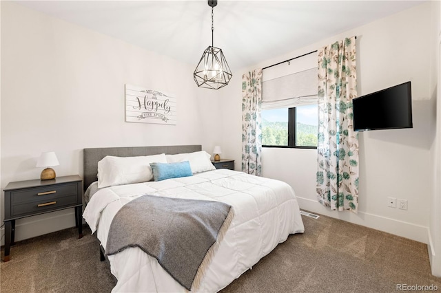 bedroom with a notable chandelier and dark carpet