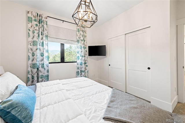 carpeted bedroom featuring an inviting chandelier and a closet