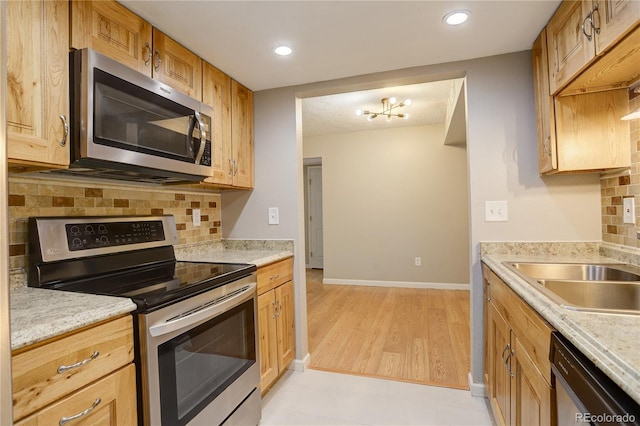 3550 S Harlan St Unit 259, Denver, CO 80235 - kitchen with stainless steel appliances, decorative backsplash, light countertops, a sink, and baseboards