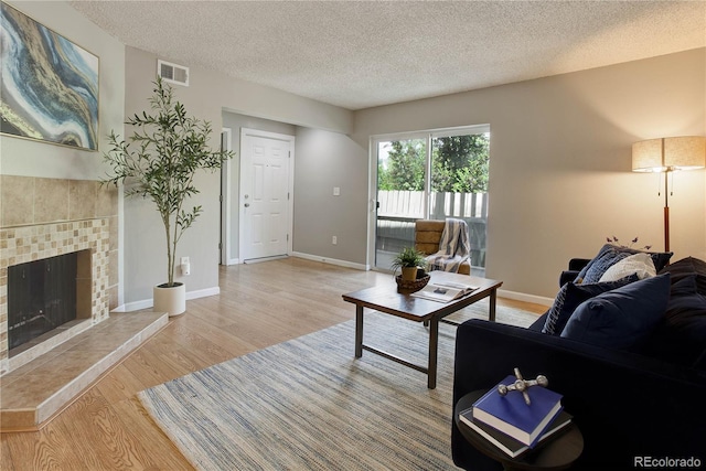 3550 S Harlan St Unit 259, Denver, CO 80235 - living room with wood finished floors, a textured ceiling, a tile fireplace, and baseboards