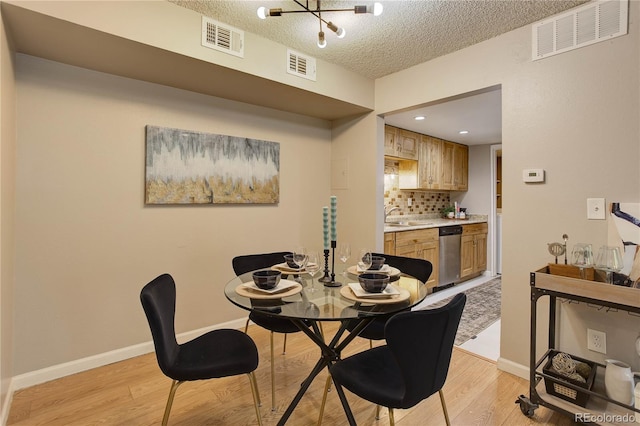 3550 S Harlan St Unit 259, Denver, CO 80235 - dining area featuring light wood-style floors, a textured ceiling, baseboards, and a chandelier