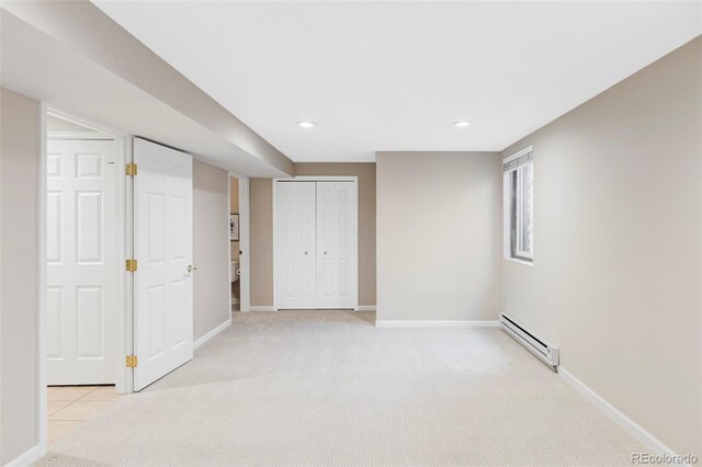 basement featuring a baseboard radiator, baseboards, and light colored carpet