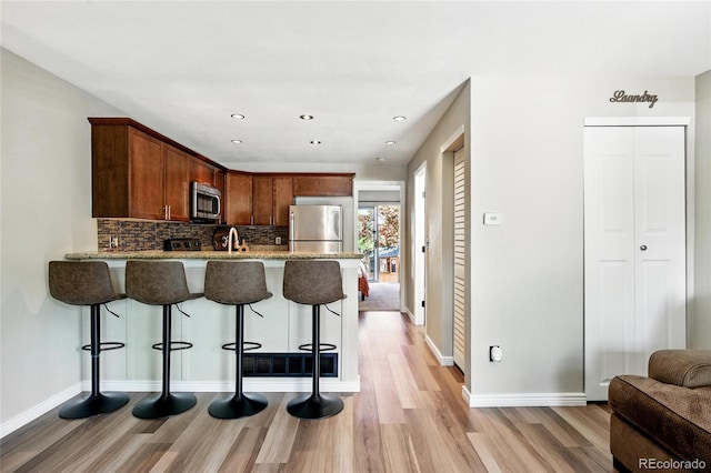 1172 S Zeno Way Unit F, Aurora, CO 80017 - kitchen featuring appliances with stainless steel finishes, light wood-style flooring, a peninsula, tasteful backsplash, and recessed lighting