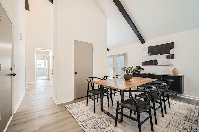 dining room featuring high vaulted ceiling, light wood-style flooring, beam ceiling, and french doors