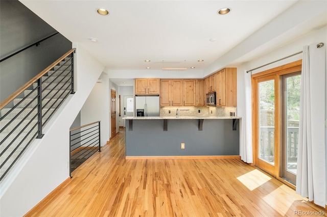101 Lions Ln, Minturn, CO 81645 - kitchen with appliances with stainless steel finishes, a peninsula, light wood-style floors, recessed lighting, and a breakfast bar area