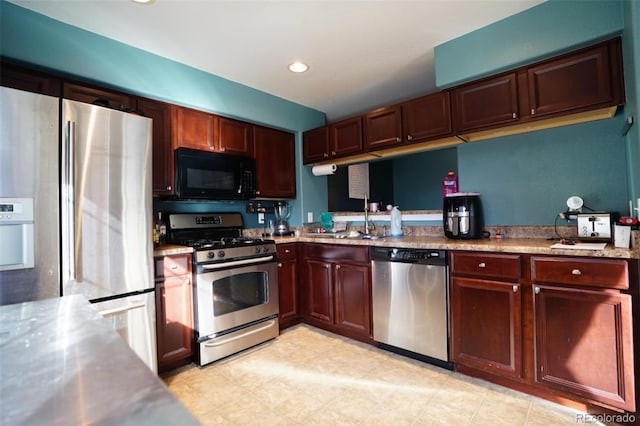 kitchen featuring appliances with stainless steel finishes, sink, and light stone counters