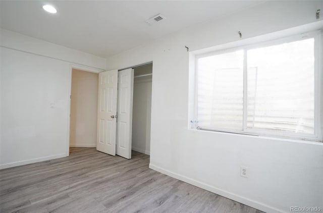 unfurnished bedroom with a closet and light wood-type flooring